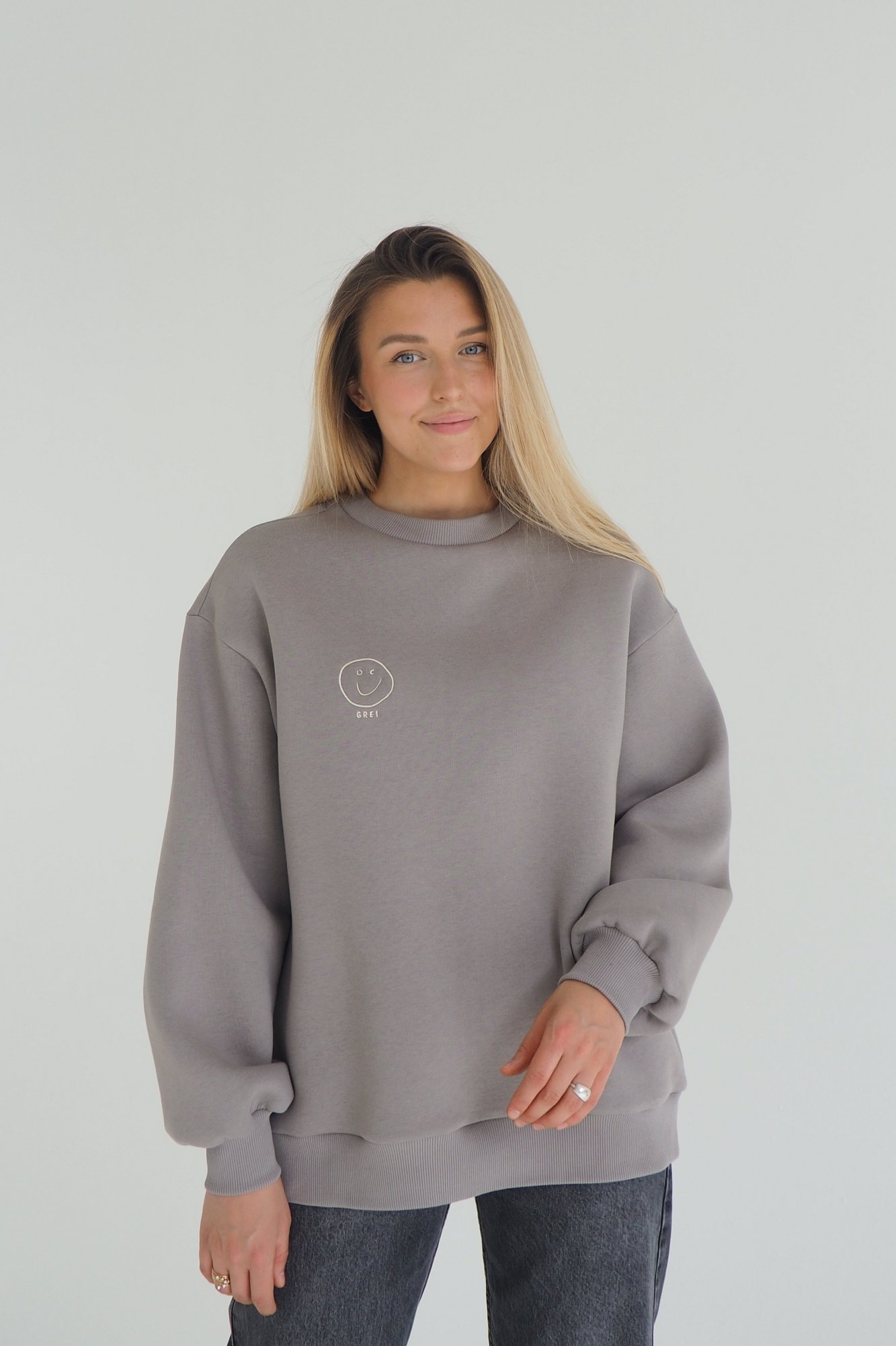 CLOUD sweatshirt is inspired by the cozy puffiness that wraps you in comfort. This oversized sweatshirt is embroidered with the signature GREI studio charm – SMILE. With a lowered shoulder seam and puffed sleeve ends. Oversized fit for ultimate comfort Puffed sleeve ends for a cozy, voluminous appearance Ribbed crew neck, cuffs, and bottom hem for a classic finish Embroidered with the GREI studio SMILE charm Made from long-lasting fabric: 65% cotton, 35% polyester