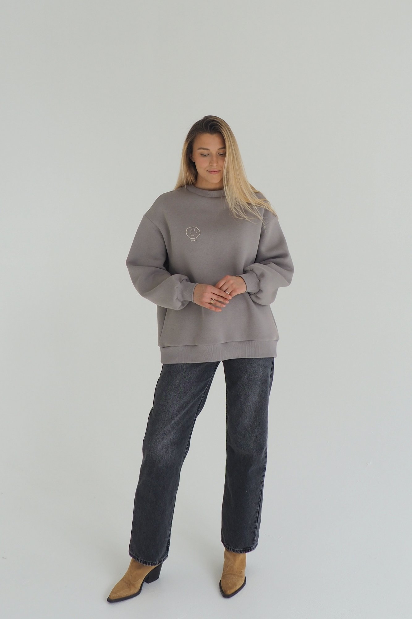 CLOUD sweatshirt is inspired by the cozy puffiness that wraps you in comfort. This oversized sweatshirt is embroidered with the signature GREI studio charm – SMILE. With a lowered shoulder seam and puffed sleeve ends. Oversized fit for ultimate comfort Puffed sleeve ends for a cozy, voluminous appearance Ribbed crew neck, cuffs, and bottom hem for a classic finish Embroidered with the GREI studio SMILE charm Made from long-lasting fabric: 65% cotton, 35% polyester